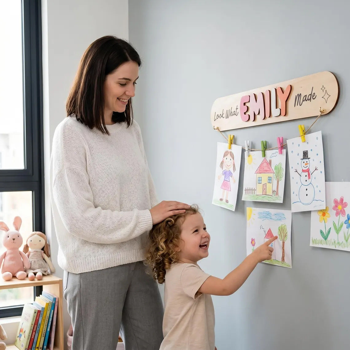 Mother and kid hanging children drawings on custom name art display board
