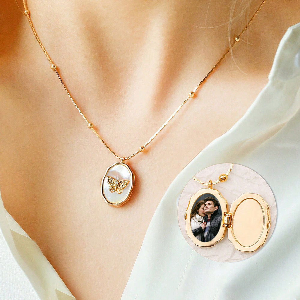 Female collarbone wear shot of gold plated brass locket with natural shell butterfly, showing open inner photo compartment