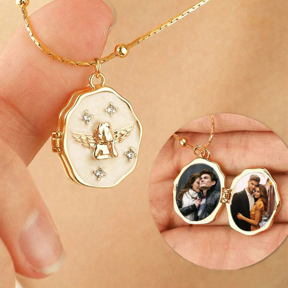 Hand-held shot of gold brass embossed angel locket showing two built-in photo slots with custom couple photos