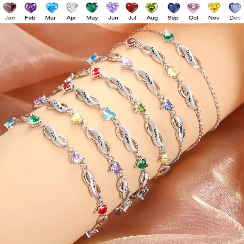 Stacked wearing display of multiple brass infinity bracelets with different heart birthstone zircon on human arm