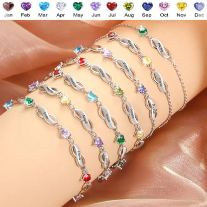 Stacked wearing display of multiple brass infinity bracelets with different heart birthstone zircon on human arm