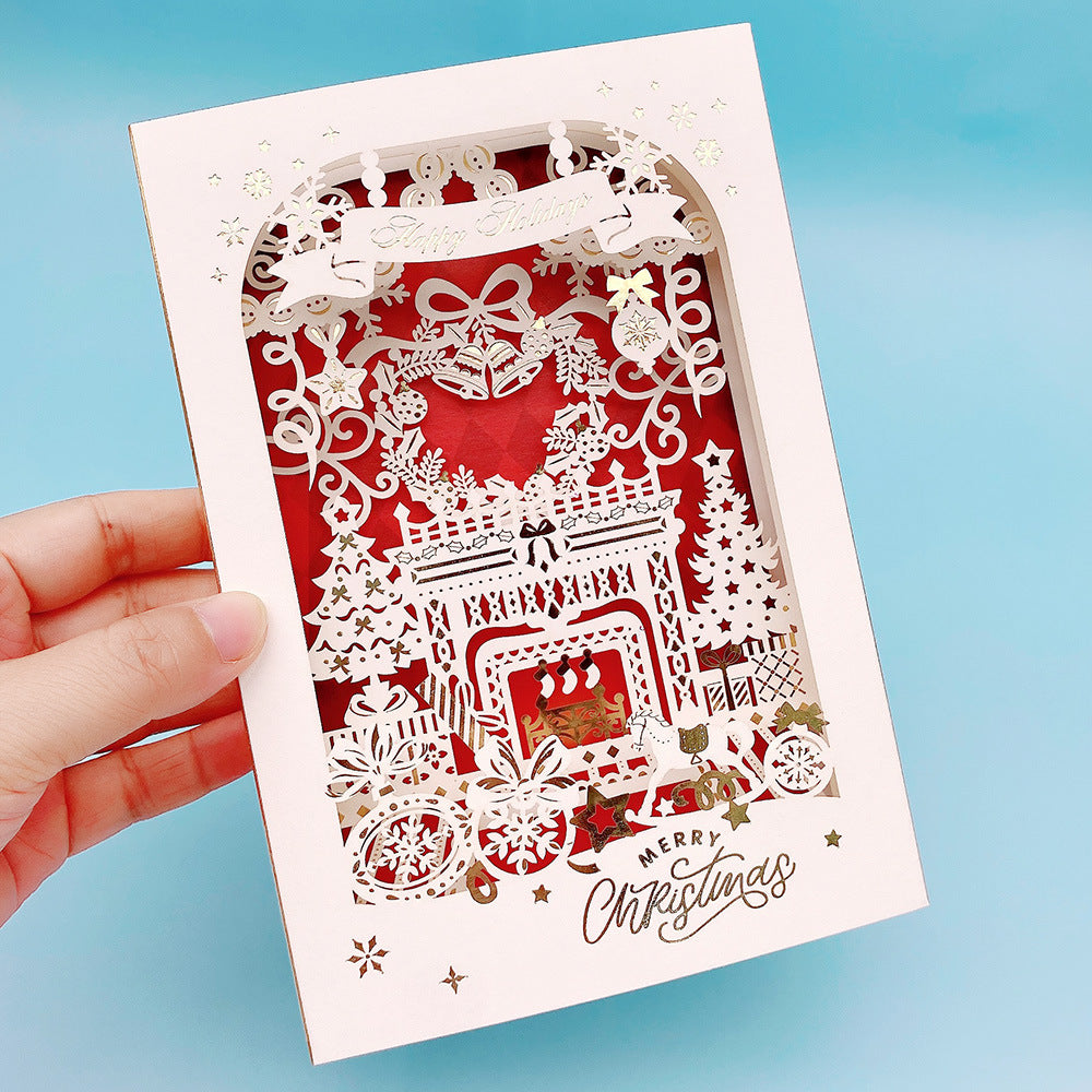 Red winter village laser cut 3D layered Christmas pop up card held in hand