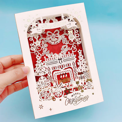 Red winter village laser cut 3D layered Christmas pop up card held in hand