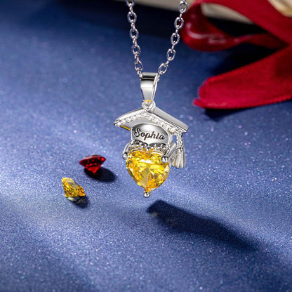 Silver brass engraved graduation cap necklace with yellow heart zircon shot on dark fabric background