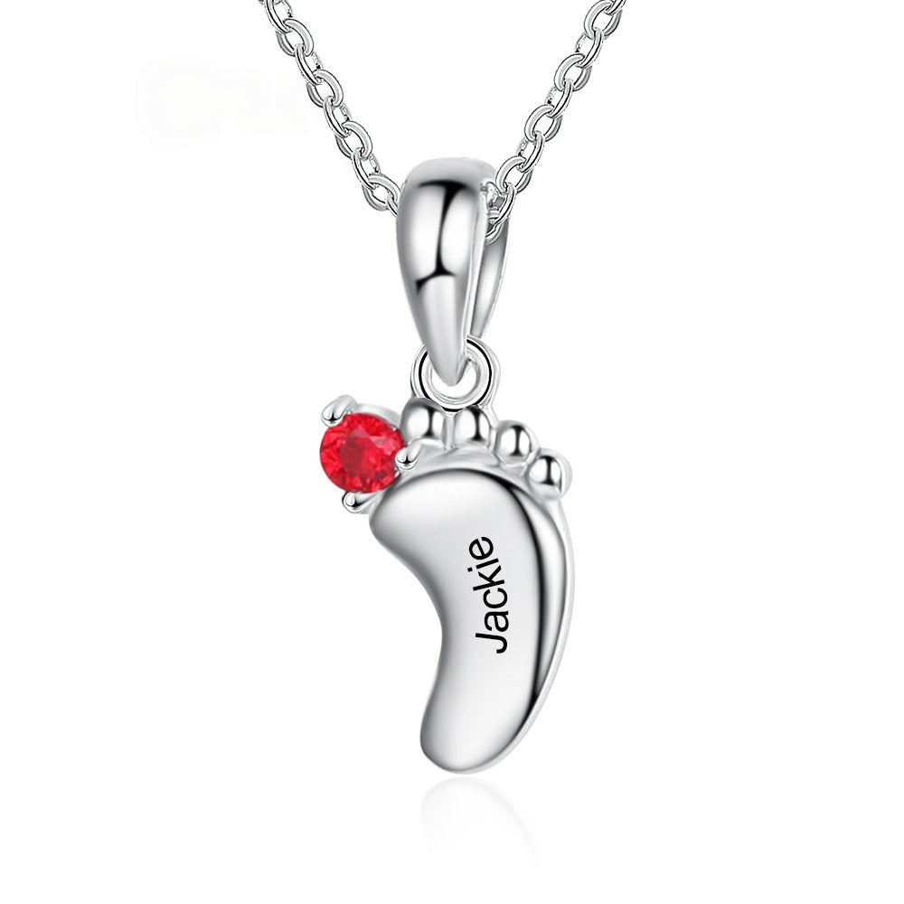 Single baby footprint brass pendant with red birthstone zircon and personalized engraved text on white background