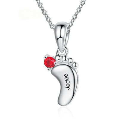Single baby footprint brass pendant with red birthstone zircon and personalized engraved text on white background