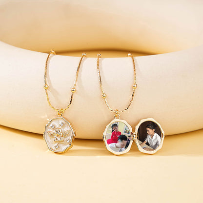 Two brass angel enamel lockets placed together, showing locket closed state and internal photo placement effect