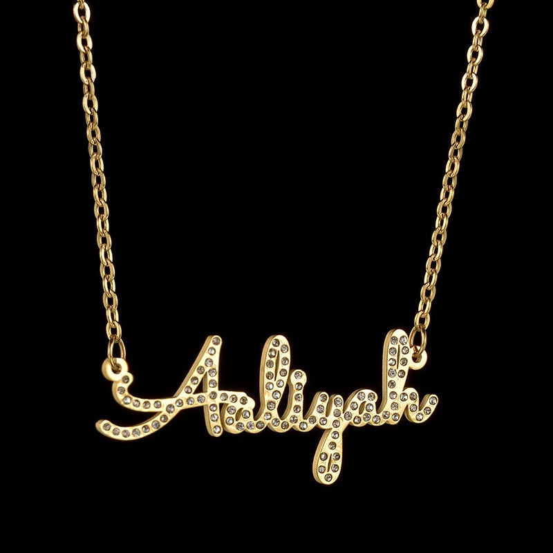 Highlights shot of stainless steel cursive name necklace with cubic zirconia against pure black background